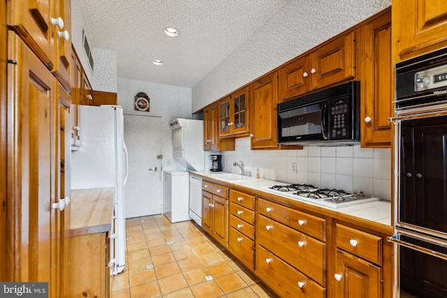 kitchen featuring tasteful backsplash, tile countertops, black appliances, a textured ceiling, and sink