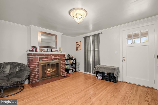 living room with ornamental molding, light wood-type flooring, and a brick fireplace