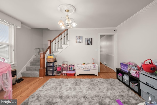 recreation room featuring ornamental molding, light hardwood / wood-style floors, and an inviting chandelier