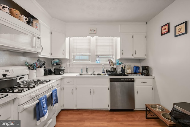 kitchen featuring white cabinets, sink, light hardwood / wood-style floors, white appliances, and crown molding