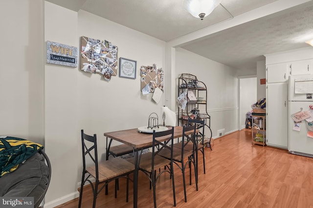 dining room featuring a textured ceiling and light hardwood / wood-style floors