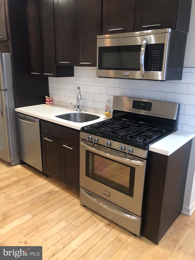 kitchen featuring dark brown cabinetry, light wood-type flooring, sink, and appliances with stainless steel finishes