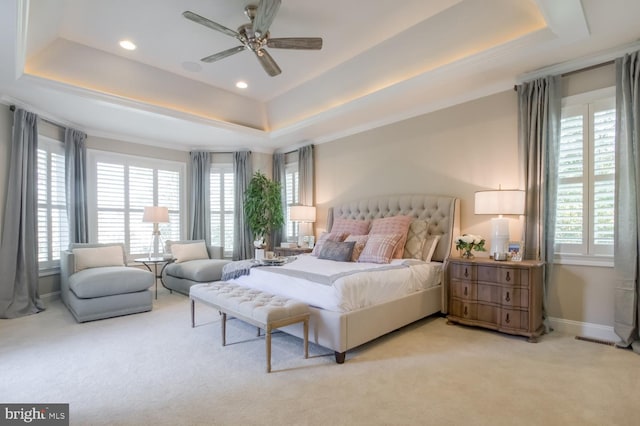 bedroom featuring ceiling fan, a raised ceiling, and multiple windows