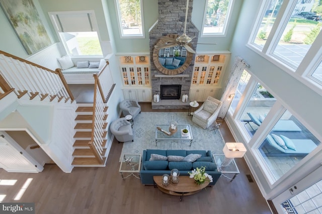 living room with wood-type flooring, a healthy amount of sunlight, a fireplace, and a high ceiling