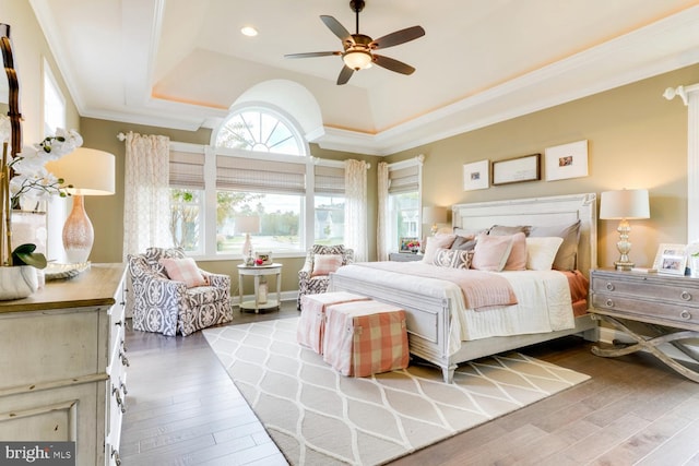 bedroom featuring ceiling fan, a raised ceiling, ornamental molding, and hardwood / wood-style flooring