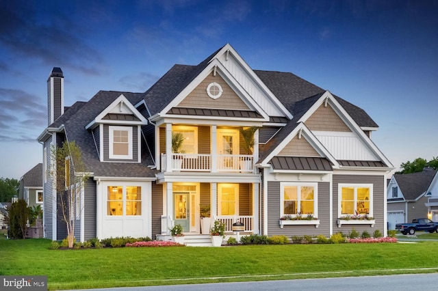 craftsman-style home with covered porch, a front lawn, and a garage