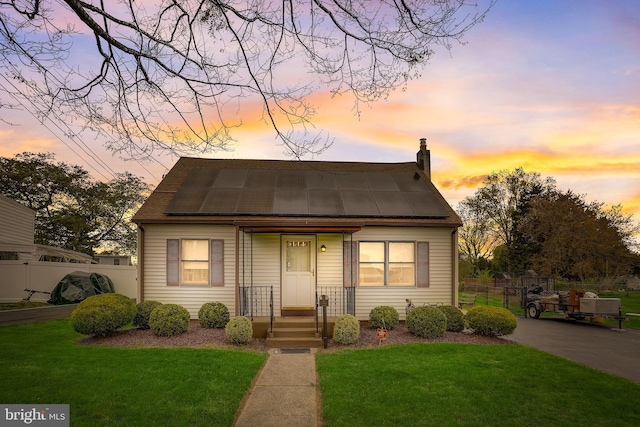 view of front of home featuring solar panels and a yard