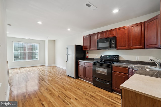 kitchen featuring sink, light wood-type flooring, and black appliances