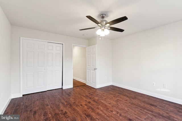 unfurnished bedroom featuring ceiling fan, a closet, and dark wood-type flooring