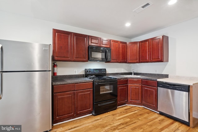 kitchen featuring sink, light hardwood / wood-style floors, and black appliances