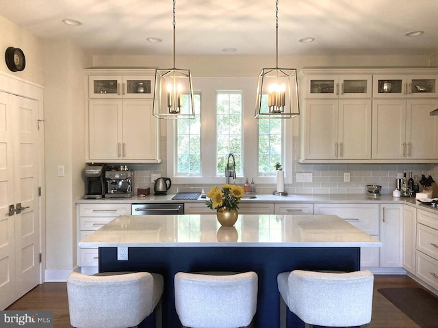 kitchen featuring dark wood-type flooring, white cabinets, stainless steel dishwasher, and a kitchen island