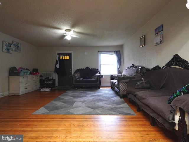 living room featuring ceiling fan, a textured ceiling, and light hardwood / wood-style floors