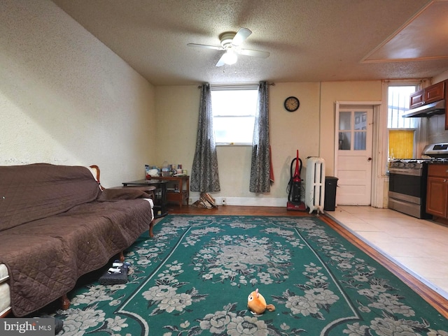 bedroom featuring ceiling fan, radiator, dark tile flooring, and a textured ceiling