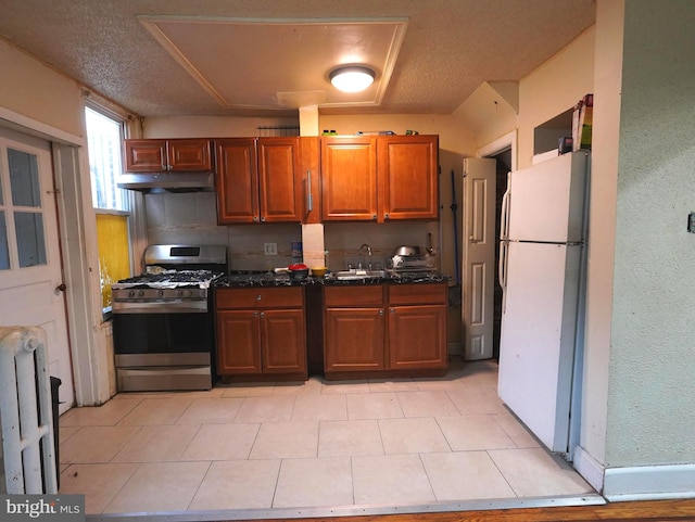 kitchen with light tile floors, tasteful backsplash, stainless steel gas stove, and white refrigerator