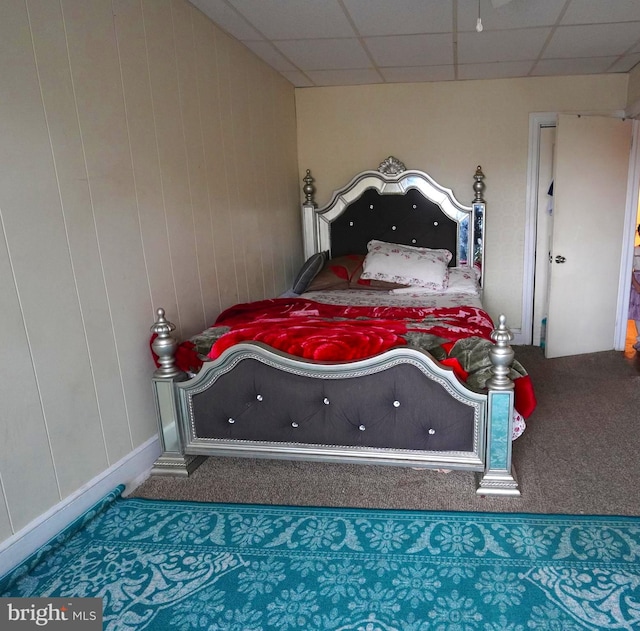 bedroom featuring dark carpet and a drop ceiling