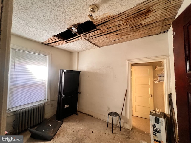 miscellaneous room with a textured ceiling and radiator heating unit