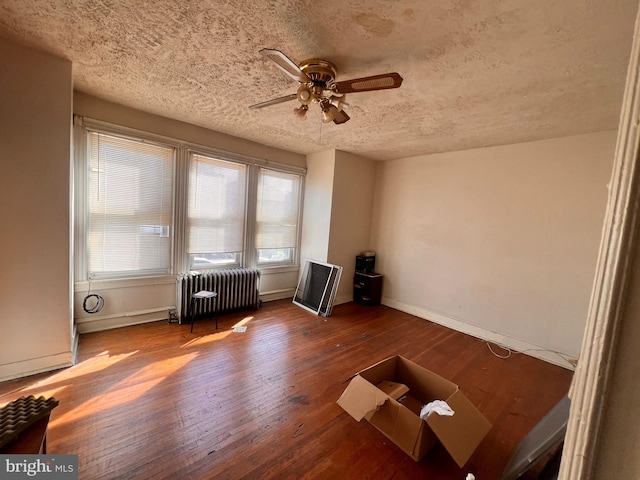 misc room with a textured ceiling, ceiling fan, hardwood / wood-style flooring, and radiator heating unit