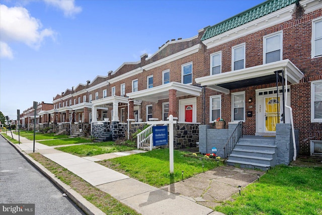 townhome / multi-family property featuring a porch and a front yard