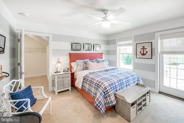 bedroom featuring a closet, a spacious closet, ceiling fan, and light colored carpet