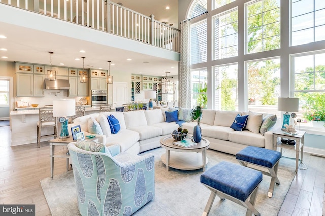 living room featuring a towering ceiling, light wood-type flooring, and a healthy amount of sunlight