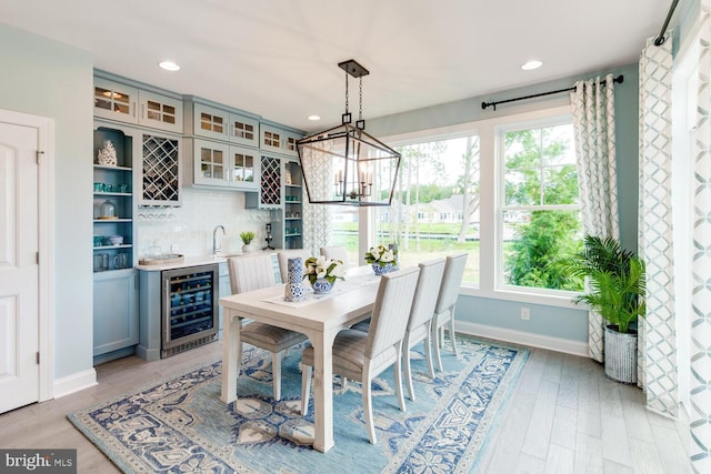 dining area featuring wine cooler, a chandelier, sink, and light hardwood / wood-style flooring