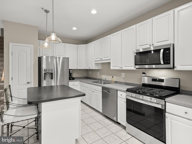 kitchen featuring appliances with stainless steel finishes, white cabinetry, a kitchen island, a kitchen bar, and decorative light fixtures