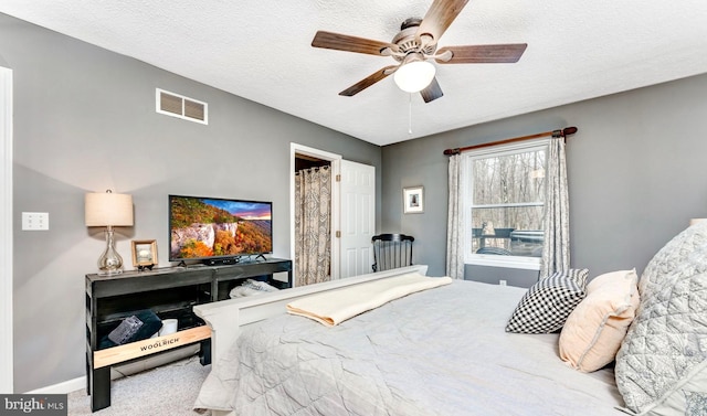 carpeted bedroom featuring ceiling fan and a textured ceiling