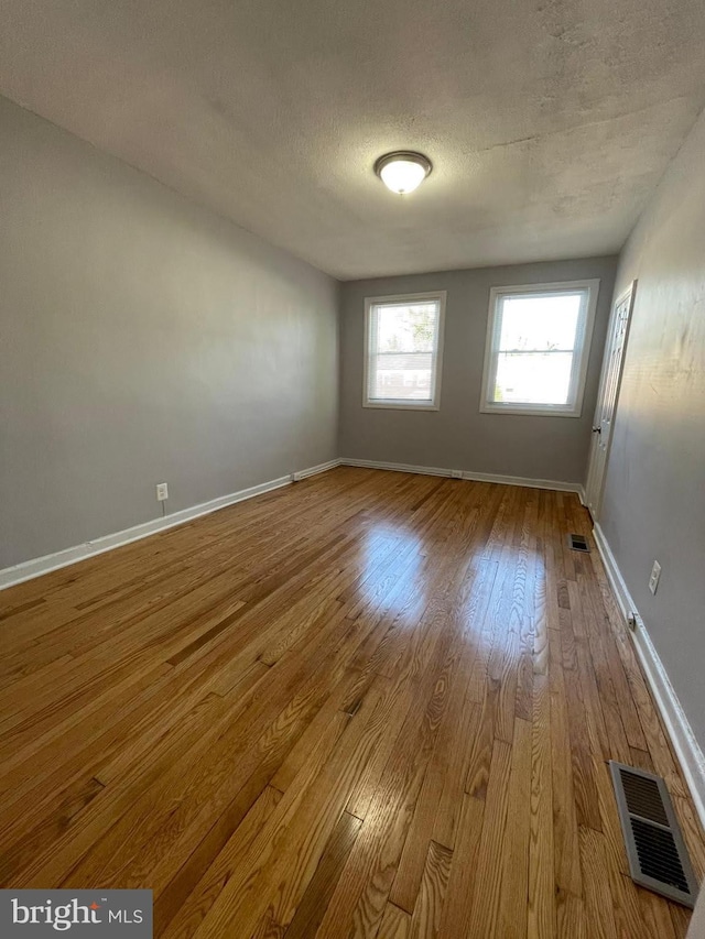 unfurnished room with a textured ceiling and light hardwood / wood-style flooring