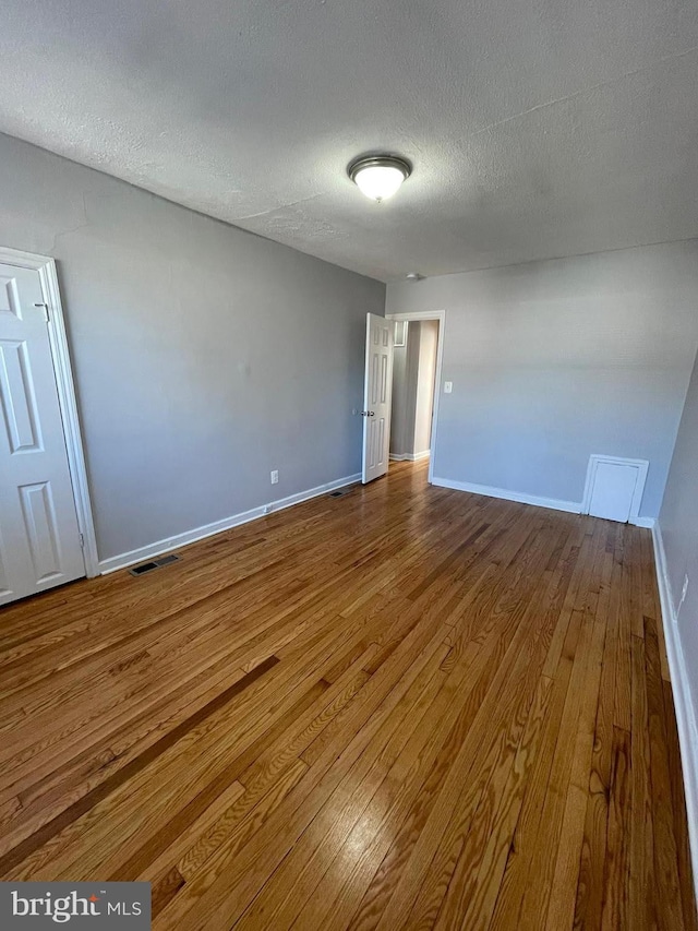 empty room with dark hardwood / wood-style flooring and a textured ceiling