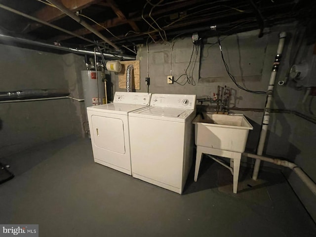 clothes washing area with washing machine and clothes dryer, water heater, and sink