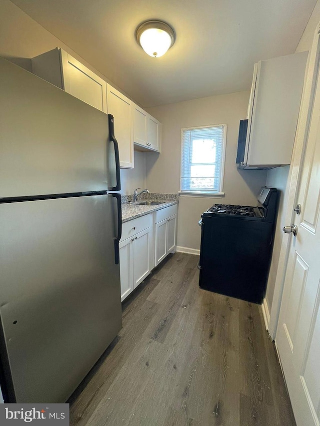 kitchen with dark hardwood / wood-style flooring, white cabinets, stainless steel refrigerator, range, and sink