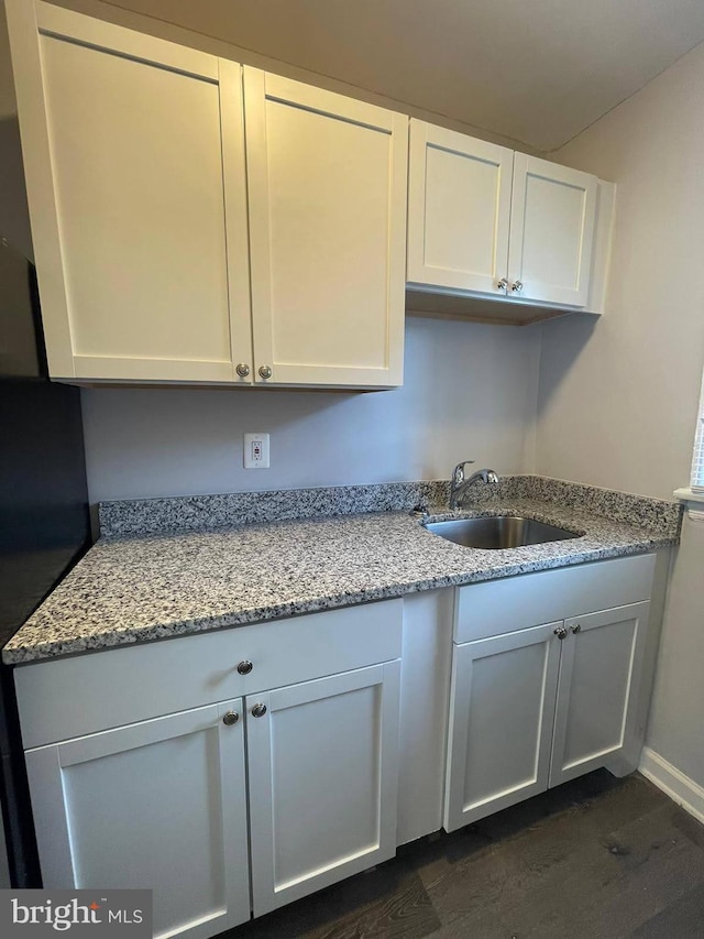 kitchen featuring white cabinets, dark hardwood / wood-style floors, sink, and light stone countertops