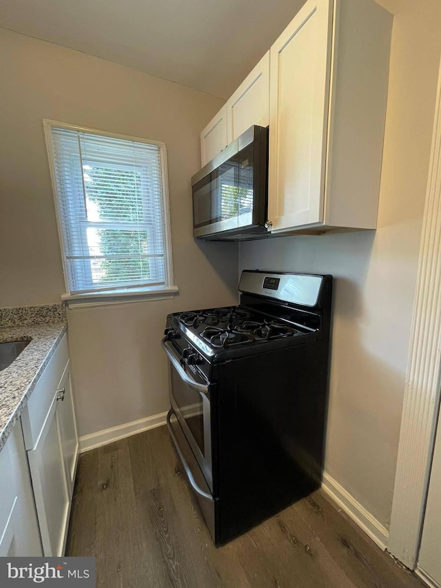 kitchen with light stone countertops, white cabinetry, range with two ovens, and dark hardwood / wood-style floors