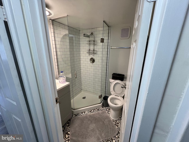 bathroom featuring a shower with door, tile floors, toilet, and vanity