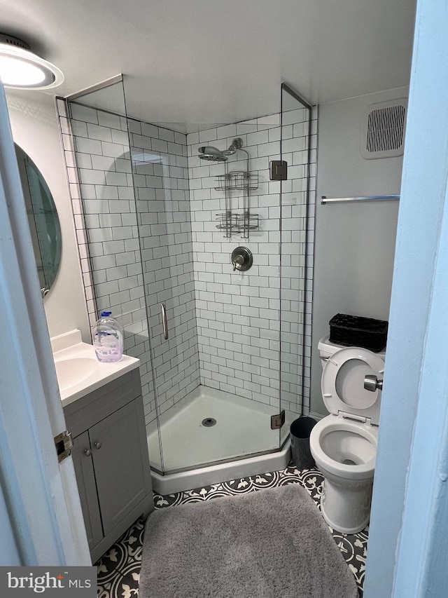 bathroom featuring walk in shower, vanity, toilet, and tile floors