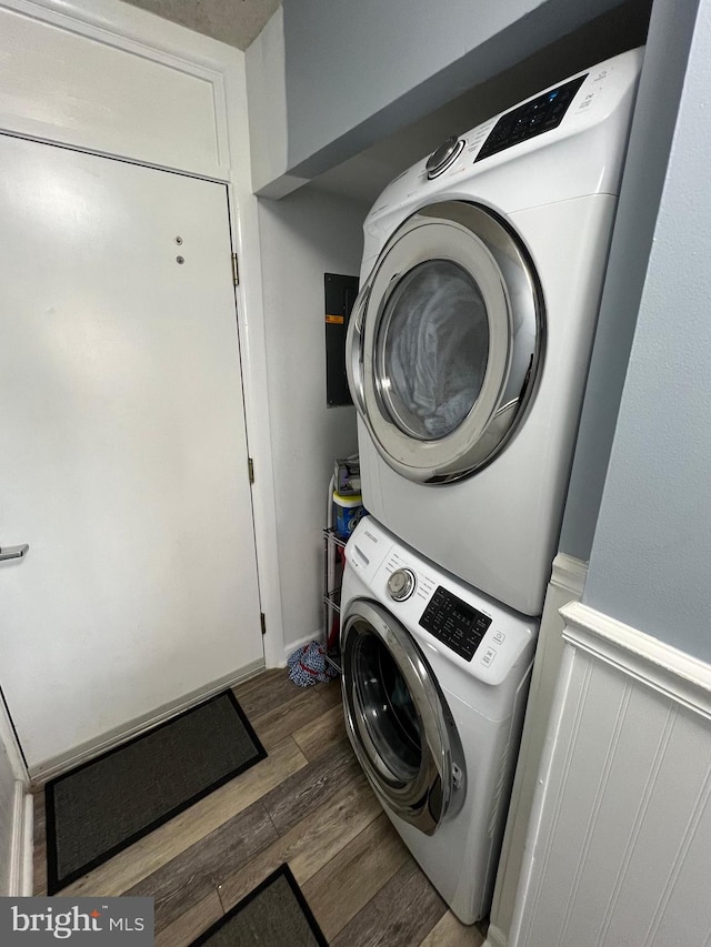 washroom with stacked washing maching and dryer and dark hardwood / wood-style flooring