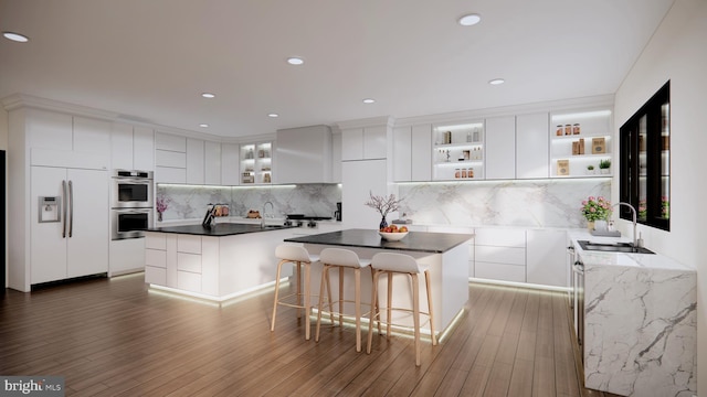 kitchen featuring hardwood / wood-style floors, white built in fridge, a center island, and white cabinets