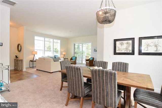 carpeted dining area with a chandelier