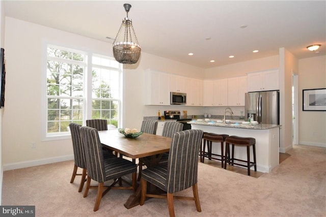 dining room featuring a chandelier, sink, and light colored carpet