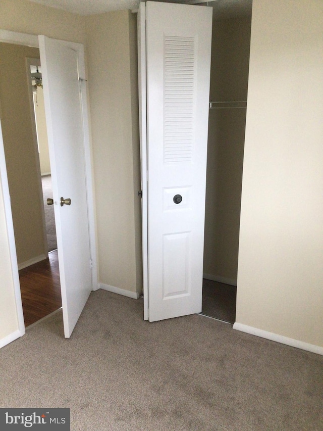 unfurnished bedroom with a closet and dark colored carpet