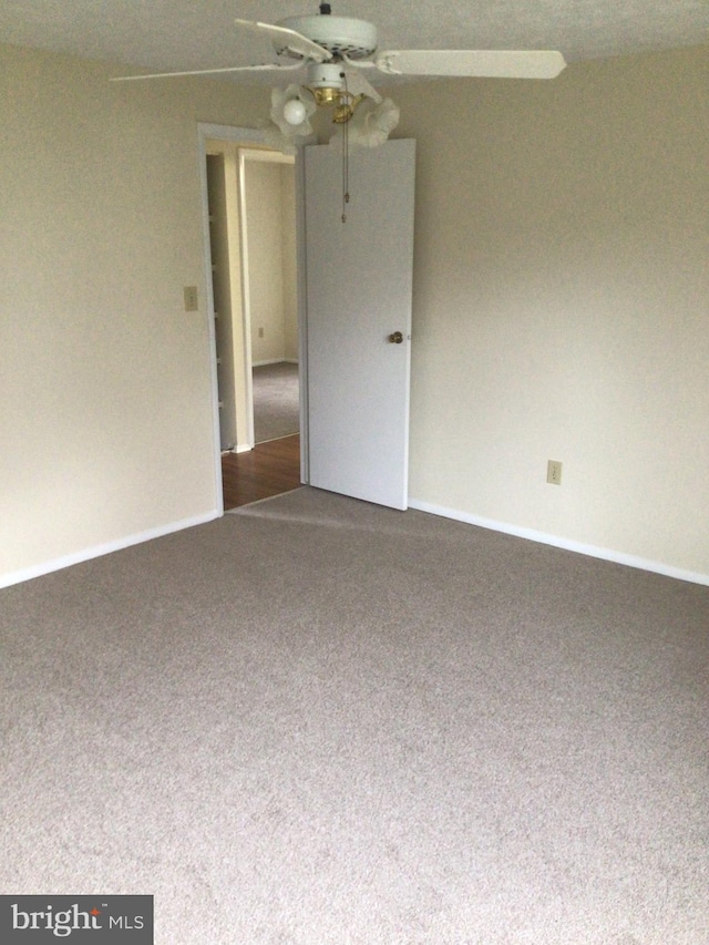 carpeted spare room featuring ceiling fan