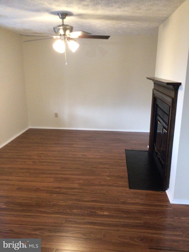 unfurnished living room featuring dark hardwood / wood-style floors, a textured ceiling, and ceiling fan