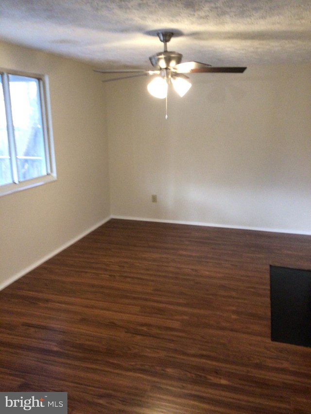 spare room with ceiling fan, a textured ceiling, and dark wood-type flooring