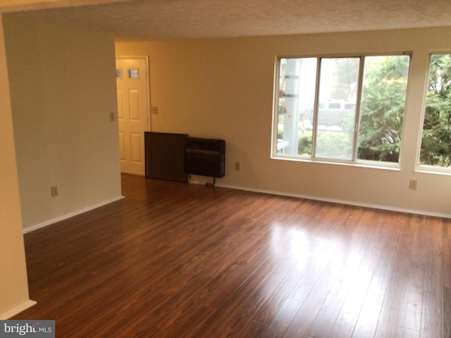 spare room with plenty of natural light and dark wood-type flooring