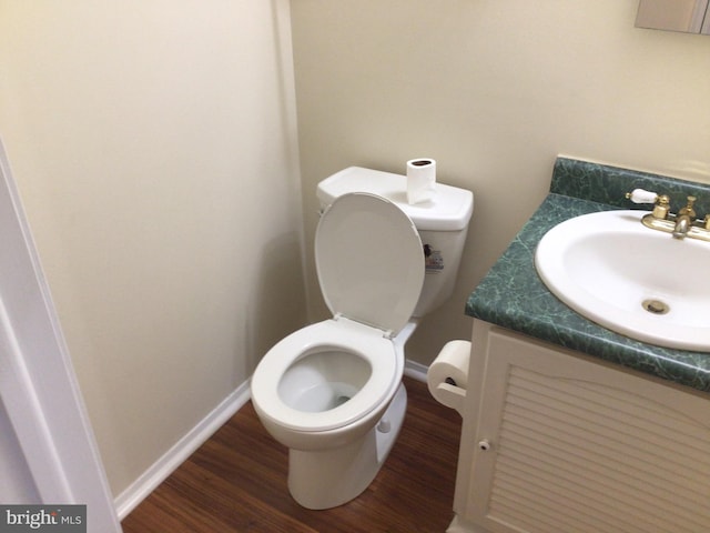 bathroom with toilet, vanity, and wood-type flooring