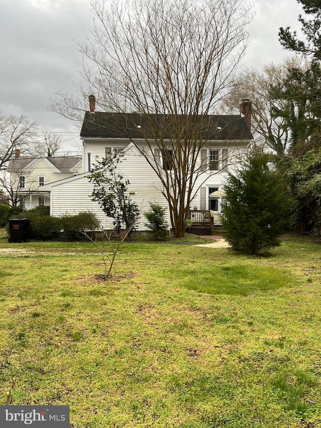 view of side of home with a chimney and a lawn