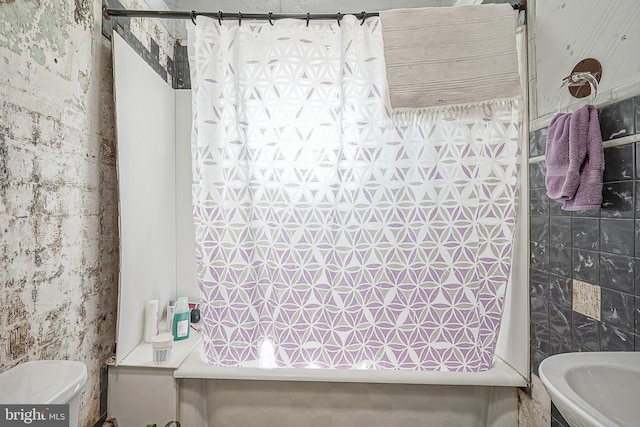 bathroom featuring toilet and tile walls