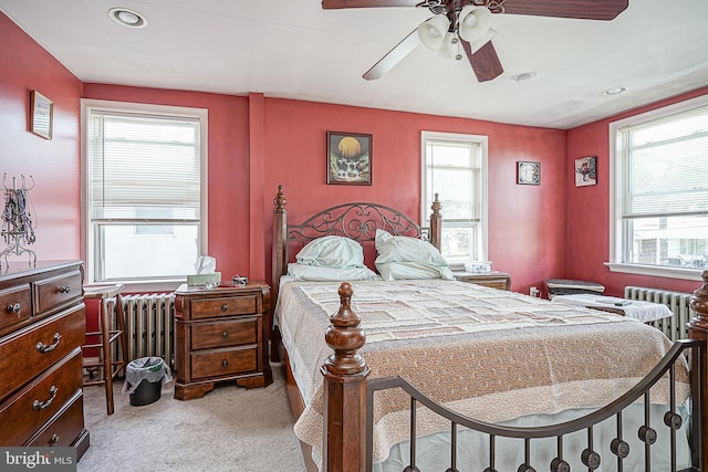 carpeted bedroom with radiator, ceiling fan, and multiple windows