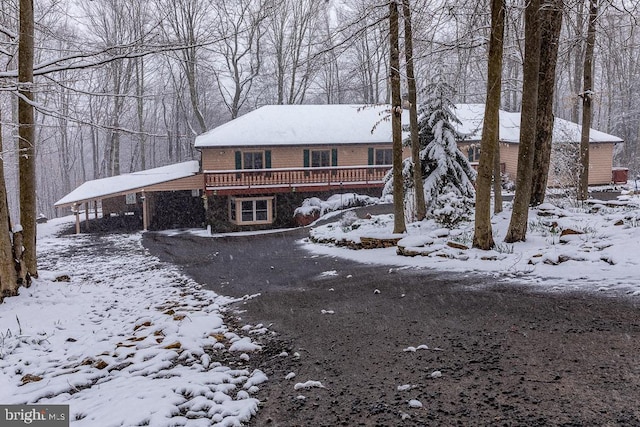 snow covered rear of property with a carport and a deck