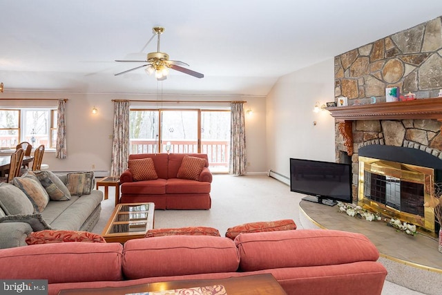 carpeted living room featuring baseboard heating, a stone fireplace, vaulted ceiling, and plenty of natural light